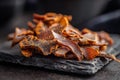 Beef jerky. Dried spiced meat on black table Royalty Free Stock Photo