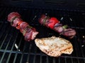 Beef kebob with onions and peppers on a stick on a grill with chicken