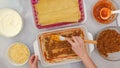 Beef lasagna step by step recipe. Assemble the lasagna. Woman hands spreading layer of fried ground beef on top of noodles