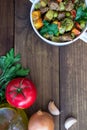 Beef meat stewed with vegetables in ceramic pot with ingredients on wooden background Royalty Free Stock Photo