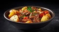 Beef meat and vegetables stew in black bowl with roasted baby potatoes. Dark background. Copy space. Top view