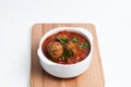 Beef meatballs in white bowl with tomato sauce served with fresh chopped spinach or basil on wooden board. Light background, copy Royalty Free Stock Photo