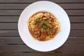 Beef ragout with red bell peppers and mushrooms with parsley garnish on pasta in a white plate on a rustic dark wooden table, high