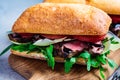 Beef sandwich with arugula, tomato and parmesan on wooden board, close up. Comfort food concept Royalty Free Stock Photo