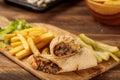 Beef Shawarma with french fries served in a cutting board isolated on wooden table background side view of fastfood Royalty Free Stock Photo