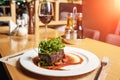 Beef steak with arugula and champignons on a white plate on the table in the restaurant. A glass of red wine, a salt, a pepper Royalty Free Stock Photo