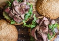 Beef steak burger with pickles, mayo sauce, arugula and red onion on a rustic wooden board, top view. Close up Royalty Free Stock Photo