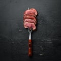 Beef steak on a fork. On a wooden background. Royalty Free Stock Photo