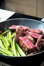 Beef steak frying on the pan with baby asparagus Royalty Free Stock Photo