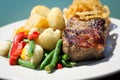 Beef steak with green beans, broccoli, potatoes and chili on white plate in restaurant Royalty Free Stock Photo