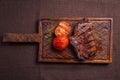 Beef steak with grilled tomatoes on a wooden board
