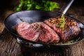 Beef steak. Juicy medium Rib Eye steak slices in pan on wooden board with fork and knife herbs spices and salt Royalty Free Stock Photo