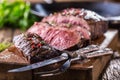 Beef steak. Juicy medium Rib Eye steak slices on wooden board with fork and knife herbs spices and salt Royalty Free Stock Photo