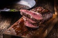 Beef steak. Juicy medium Rib Eye steak slices on wooden board with fork and knife herbs spices and salt