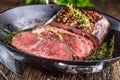 Beef steak. Juicy medium Rib Eye steak slices in pan on wooden board with fork and knife herbs spices and salt Royalty Free Stock Photo