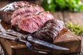 Beef steak. Juicy medium Rib Eye steak slices on wooden board with fork and knife herbs spices and salt Royalty Free Stock Photo