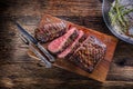 Beef steak. Juicy medium Rib Eye steak slices on wooden board with fork and knife herbs spices and salt Royalty Free Stock Photo