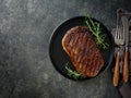 Beef Steak medium rare on black plate, surfed with tableware on black stone table with ample copy space. Dark background Royalty Free Stock Photo
