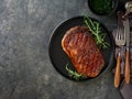 Beef Steak medium rare on black plate, surfed with tableware on black stone table with ample copy space. Dark background. Royalty Free Stock Photo