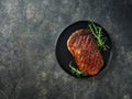 Beef Steak medium rare on black plate, surfed with tableware on black stone table with ample copy space. Dark background. Royalty Free Stock Photo