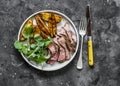 Beef steak and roast new potatoes - delicious lunch on a dark background, top view Royalty Free Stock Photo