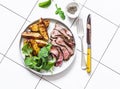 Beef steak and roast new potatoes - delicious lunch on a light background, top view Royalty Free Stock Photo