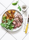 Beef steak and roast new potatoes - delicious lunch on a light background, top view Royalty Free Stock Photo