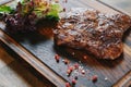 Beef steak served on wooden board plate, grilled fried meat with grill. Royalty Free Stock Photo