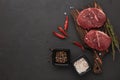 Beef steaks on cutting board and spices on black slate background. Top view. Steak menu Royalty Free Stock Photo