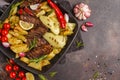 Beef steaks grilled with baked potatoes and vegetables in a pan Royalty Free Stock Photo