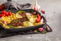 Beef steaks grilled with baked potatoes and vegetables in a pan Royalty Free Stock Photo