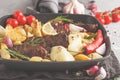 Beef steaks grilled with baked potatoes and vegetables in a pan Royalty Free Stock Photo