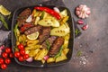 Beef steaks grilled with baked potatoes and vegetables in a pan Royalty Free Stock Photo