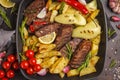 Beef steaks grilled with baked potatoes and vegetables in a pan Royalty Free Stock Photo