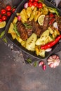 Beef steaks grilled with baked potatoes and vegetables in a pan Royalty Free Stock Photo