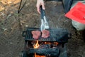 Beef steaks grilling on a cast iron plate on a camp fire. Campfire cooking. Royalty Free Stock Photo