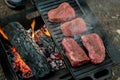 Beef steaks grilling on a cast iron plate on a camp fire. Campfire cooking. Royalty Free Stock Photo