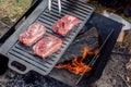Beef steaks grilling on a cast iron plate