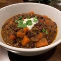 Beef stew with carrots and beans in a bowl with sour cream