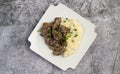 Beef stroganoff with mashed potatoes and herbs on a white square plate on a dark background Royalty Free Stock Photo