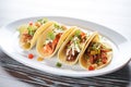 beef taco trio with various toppings on white plate Royalty Free Stock Photo