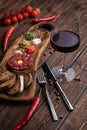 Beef Tartar with a raw egg yolk, a glass of red wine, rye bread and chilis on a wooden board with spoon and fork. Shot made from