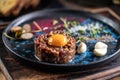 Beef tartare with egg yolk on a plate with garlic and toasted bread Royalty Free Stock Photo