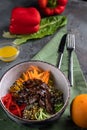 Beef Tenderloin Salad with pepper, orange, sesame seeds and herbs. Spoon and fork on a green tablecloth and gray background Royalty Free Stock Photo