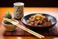 beef teriyaki with chopsticks and sake cup on bamboo mat Royalty Free Stock Photo