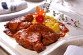 Beef in tomato sauce with yellow risotto and spices on a white plate in a restaurant Royalty Free Stock Photo
