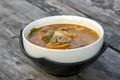 Beef Tomyam, spicy, salty, sour soup, Asian traditional food, in a white bowl on an old wooden table