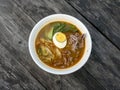 Beef Tomyam, spicy, salty, sour soup, Asian traditional food, in a white bowl on an old wooden table