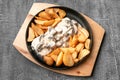 Beef tongue in creamy mushroom sauce. With baked potatoes in a rustic way. In a cast-iron pan with a wooden stand. View from above