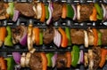 Beef and vegetable shish kebabs cooking on a grill.